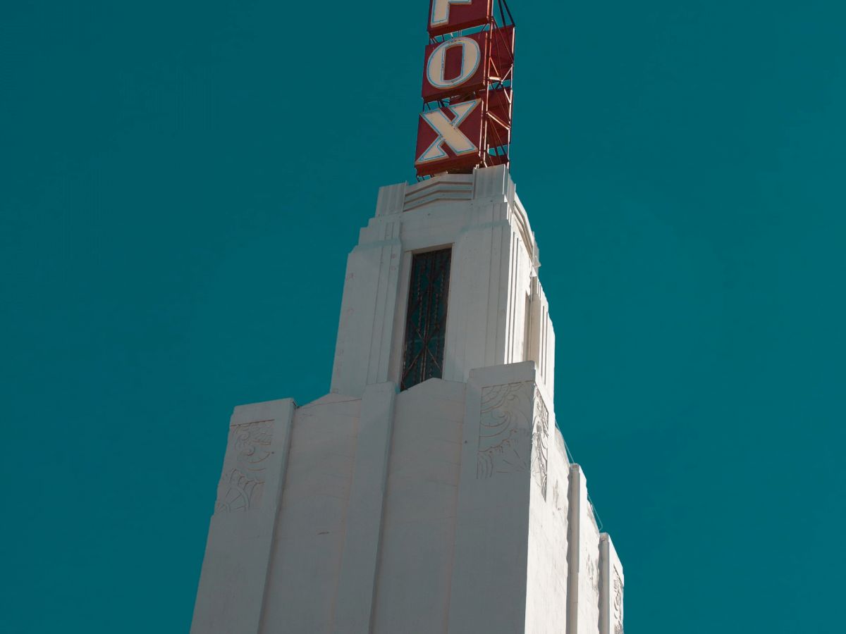 The image shows the top of a white building with a red sign reading 